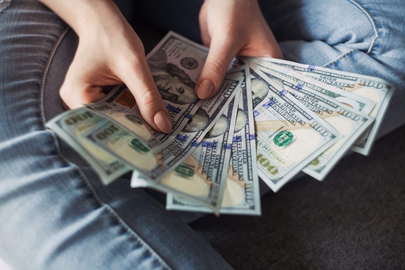 A fan of one-hundred-dollar bills held in one hand — a payoff finish line.